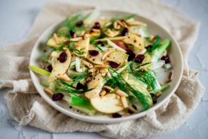 A vibrant apple and fennel salad garnished with almonds and cranberries, perfect for a healthy meal.